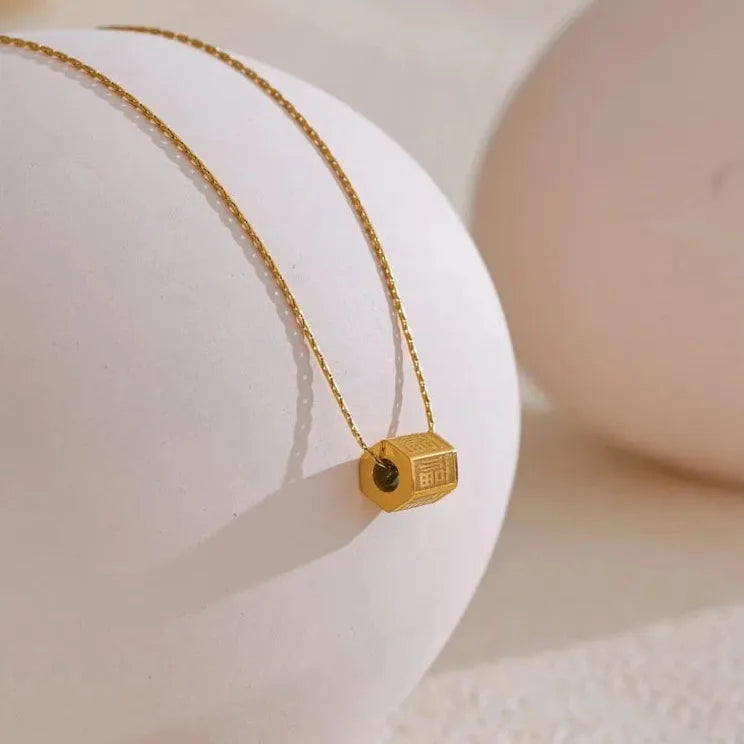 Gold necklace with a small pendant on a white surface