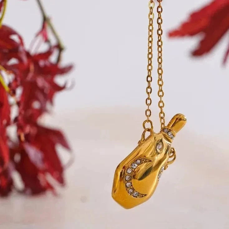 Gold necklace with a pendant against a blurred floral background