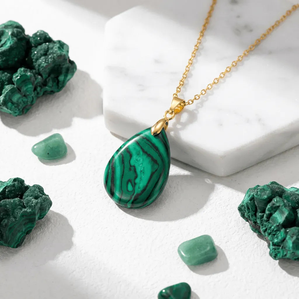 Green malachite pendant necklace on a marble surface with malachite stones.