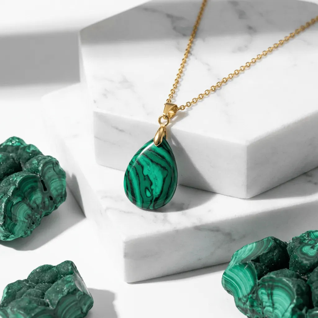 Gold necklace with a green pendant on a marble surface