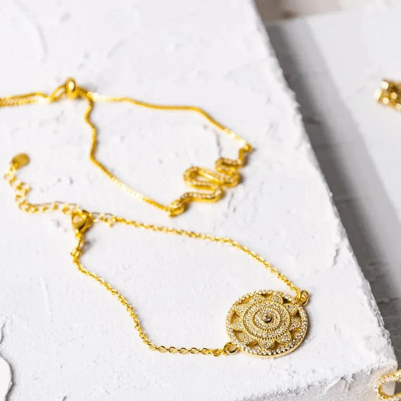 Gold necklace with intricate design on a white surface