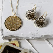 Gold necklace and earrings on a textured white surface