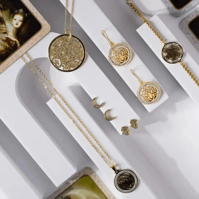 Gold jewelry set including necklaces and earrings on a white display box.