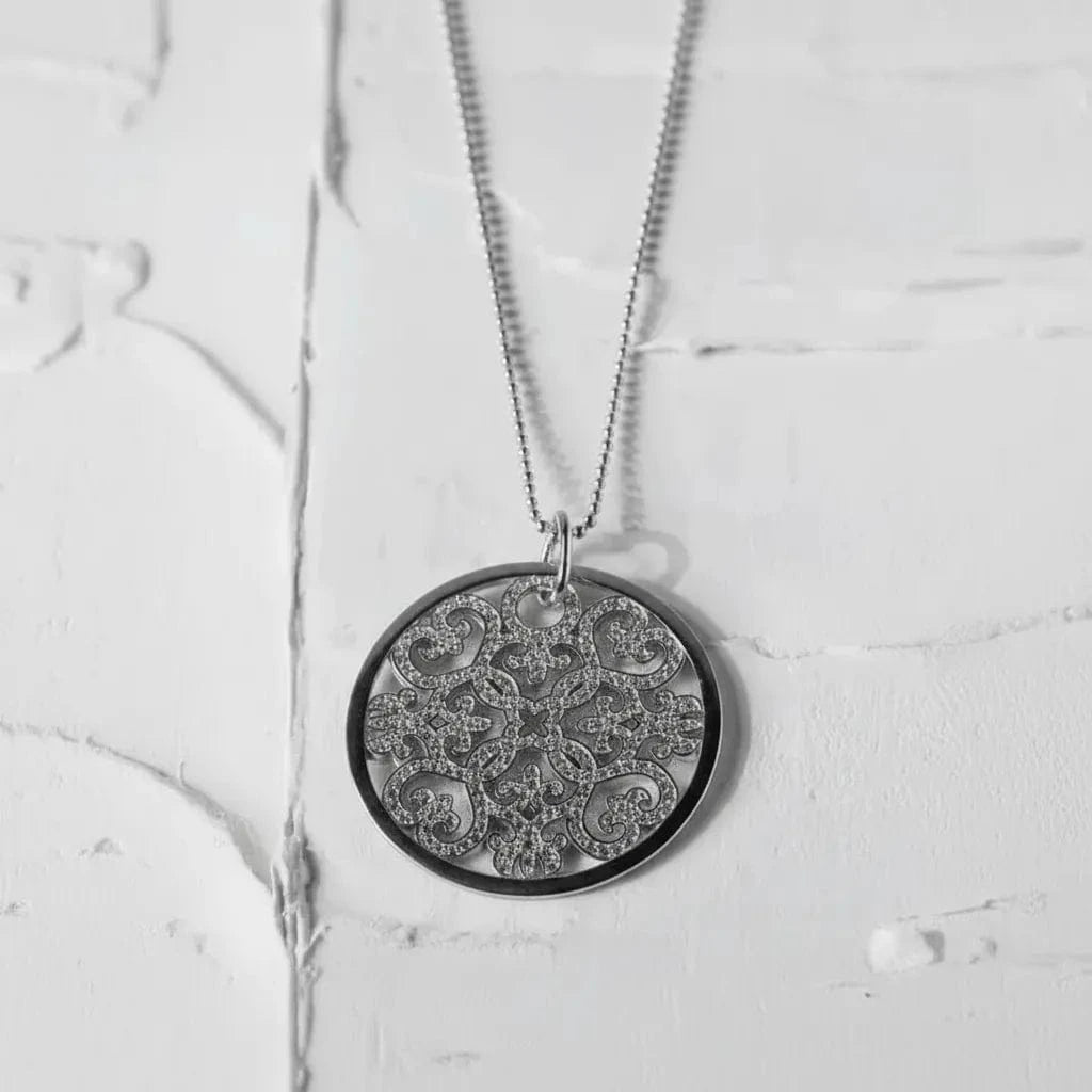 Gold necklace with a detailed pendant on a textured white surface