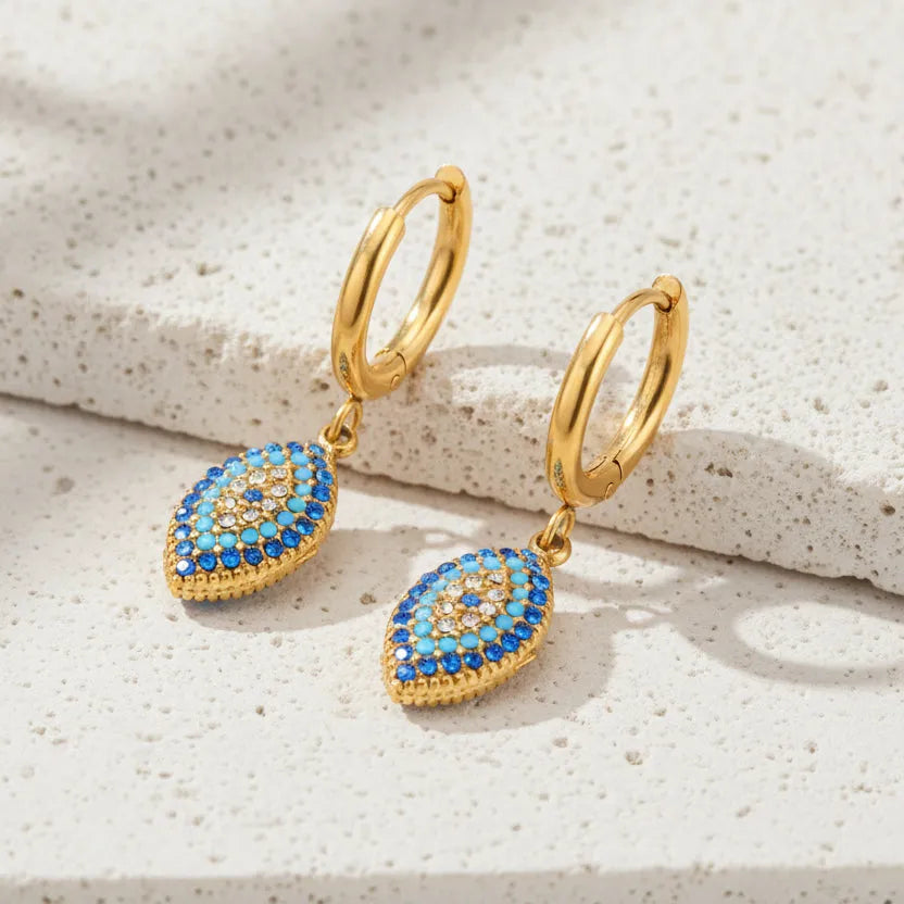 Gold hoop earrings with blue gemstones on a white background