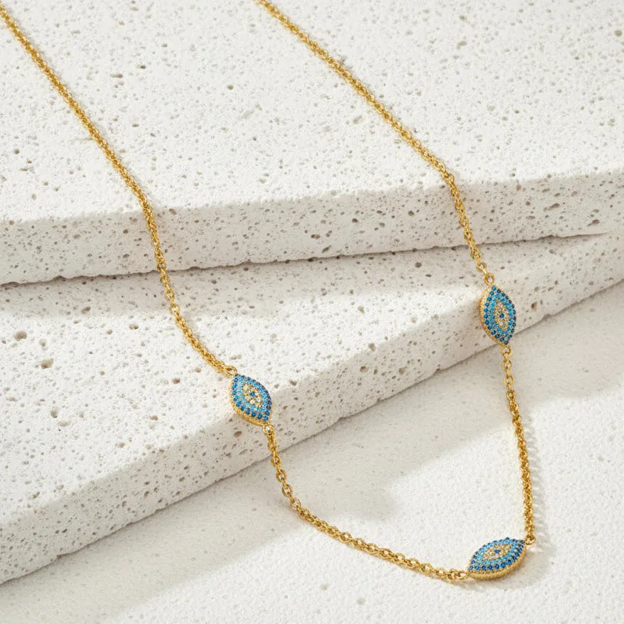Gold necklace with blue and green accents on a magazine cover with palm trees and flowers.