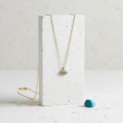 Gold plated marquise evil eye necklace with faux opal centre displayed on a jewelry stand