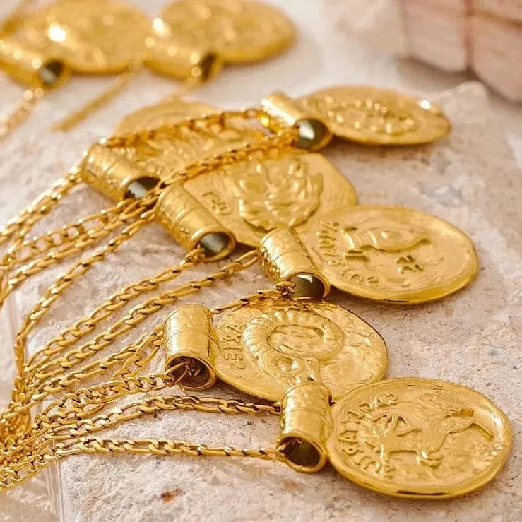 Gold necklaces with coin pendants on a textured surface