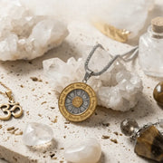 Necklace with a circular pendant on a textured surface with crystals and stones
