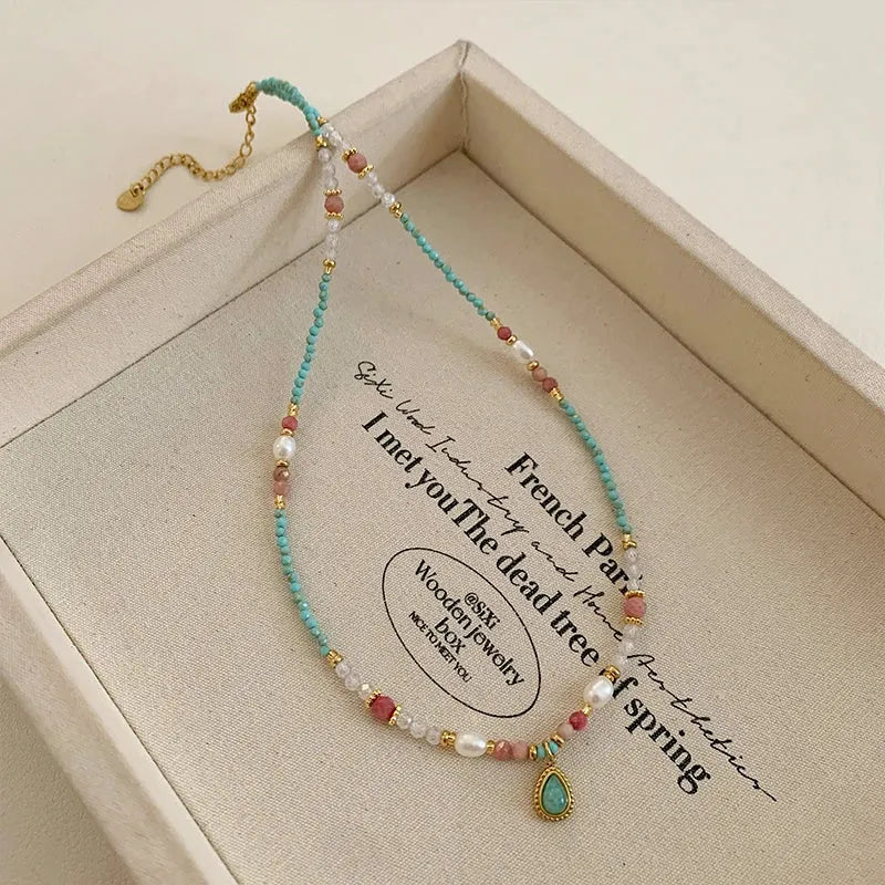 Beaded necklace with a pendant on a wooden box with text