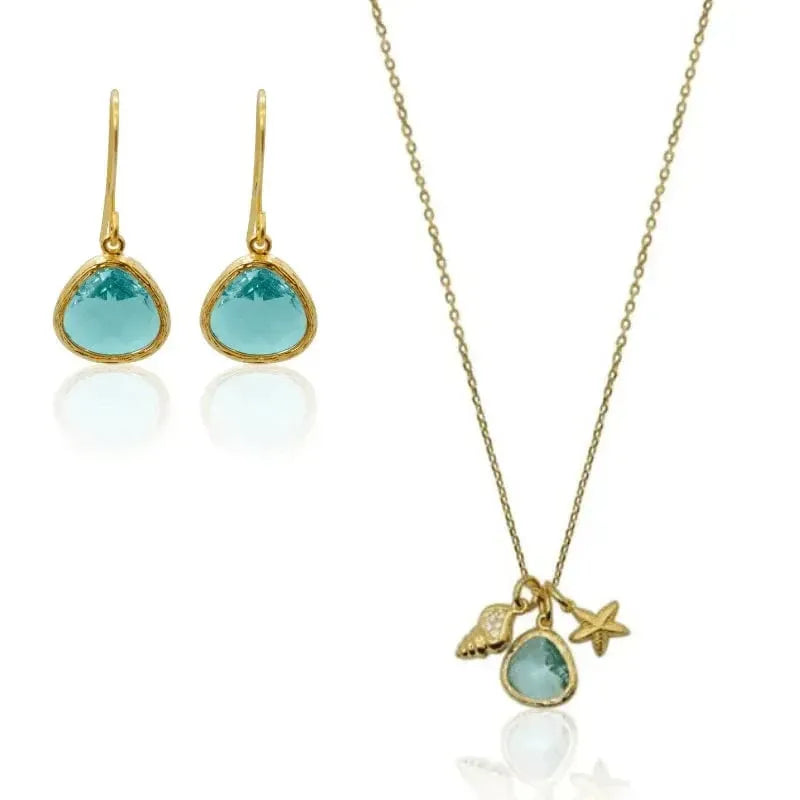 Jewelry set with gold necklace and earrings featuring blue stones on a white background