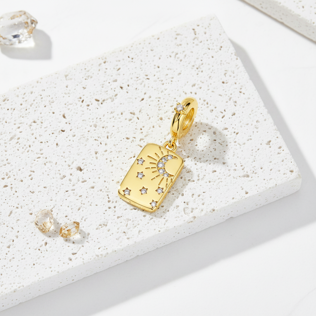 Gold-plated moon and star rectangular pendant lying flat on a white stone block