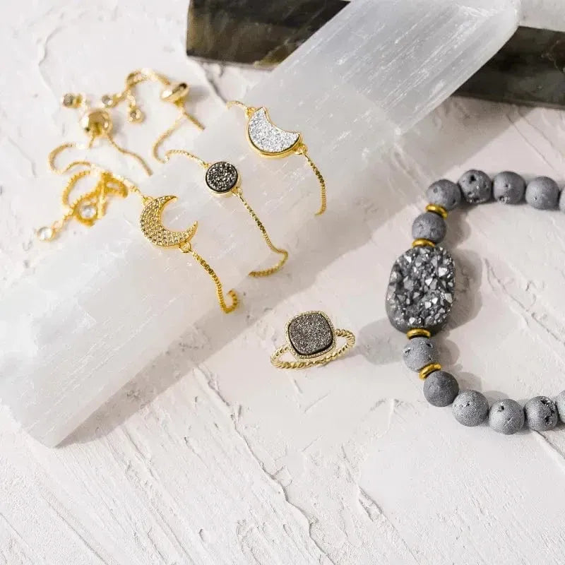 Gold and gray jewelry on a textured white surface with crystals.