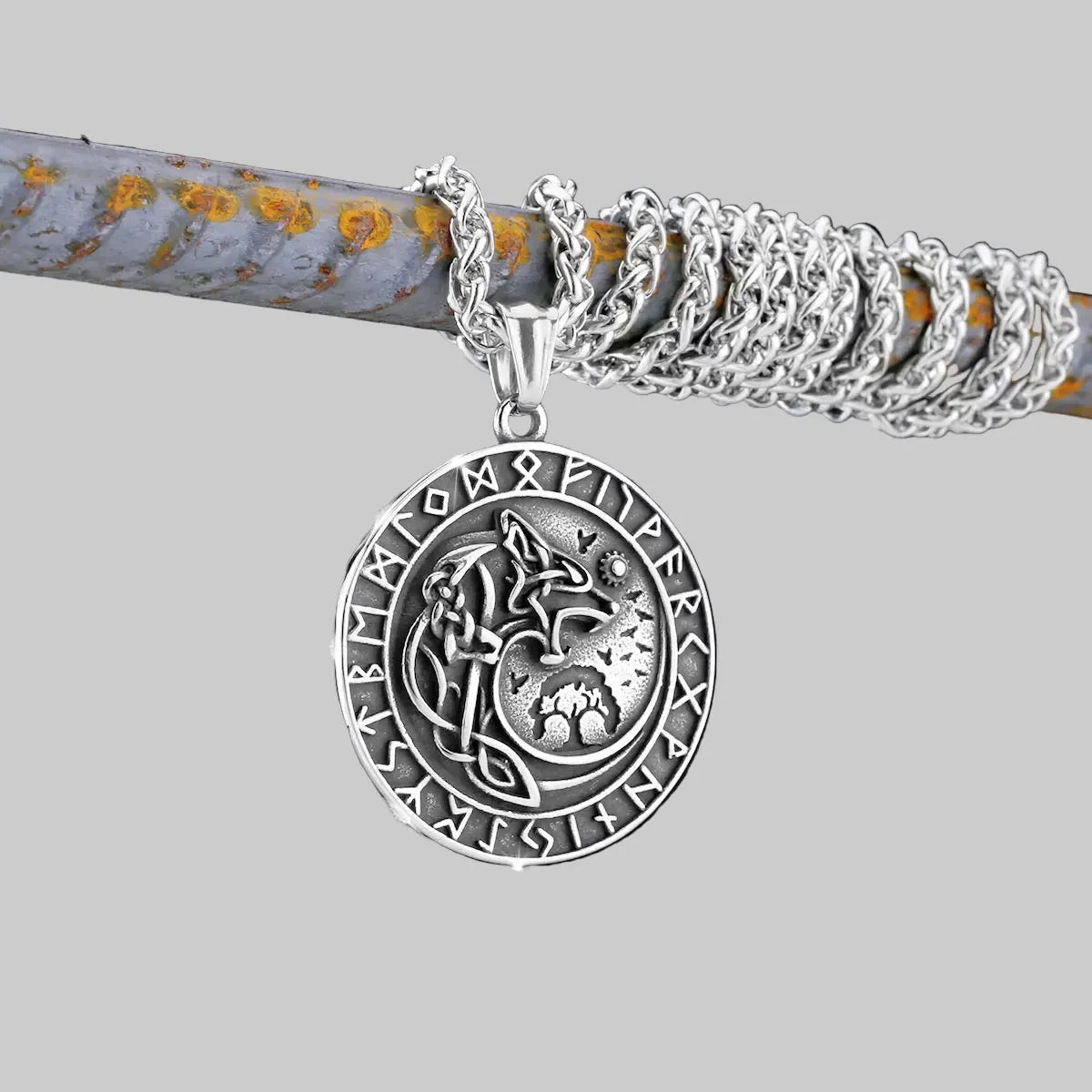 Silver pendant with wolf design on a chain against a dark background