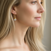 Gold earrings with white stones on a soft white background