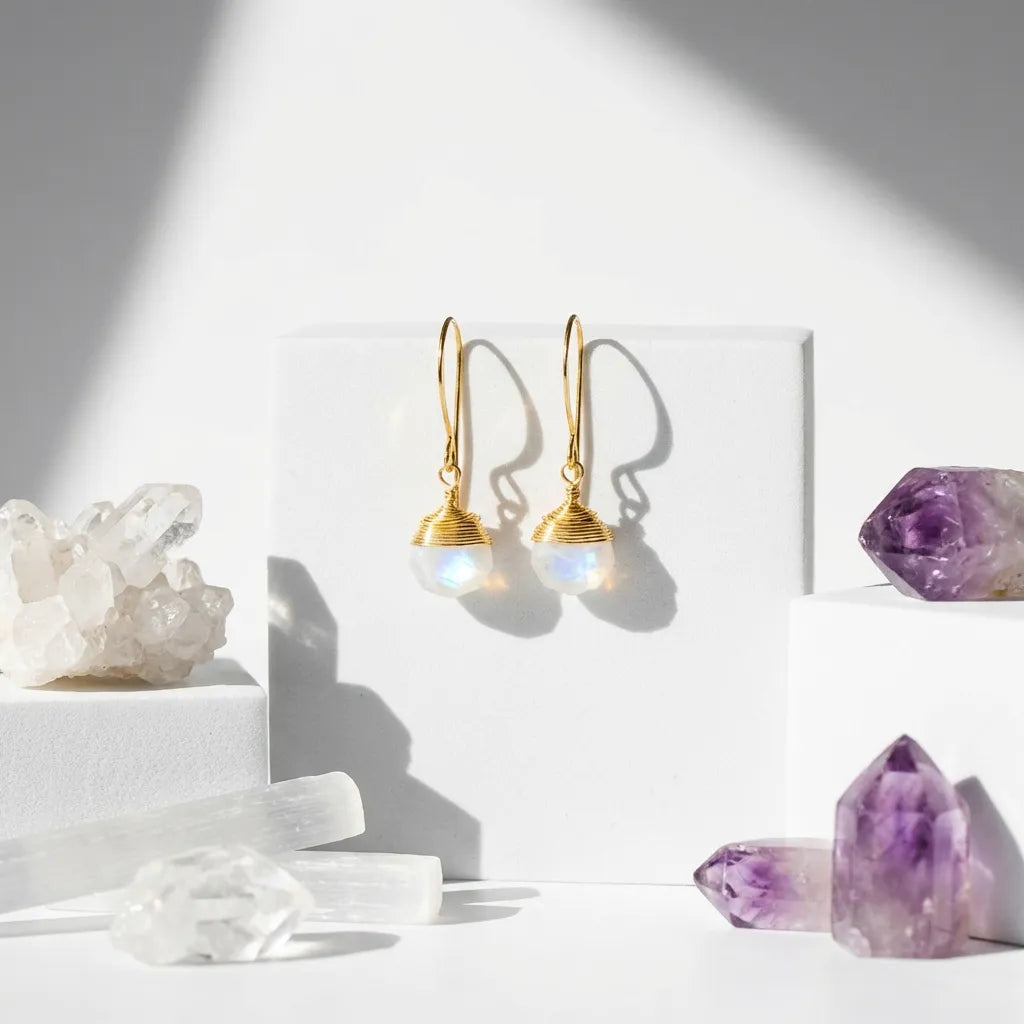 Gold earrings with gemstones on a white surface with crystals