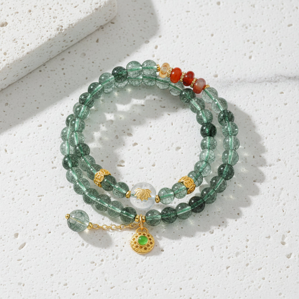 Stack of green beaded bracelets with gold and silver charms on a white background