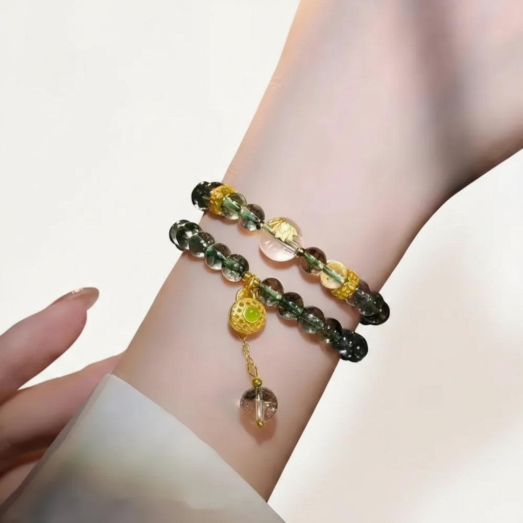 Green crystal gold jewelry on a wrist with a dark background