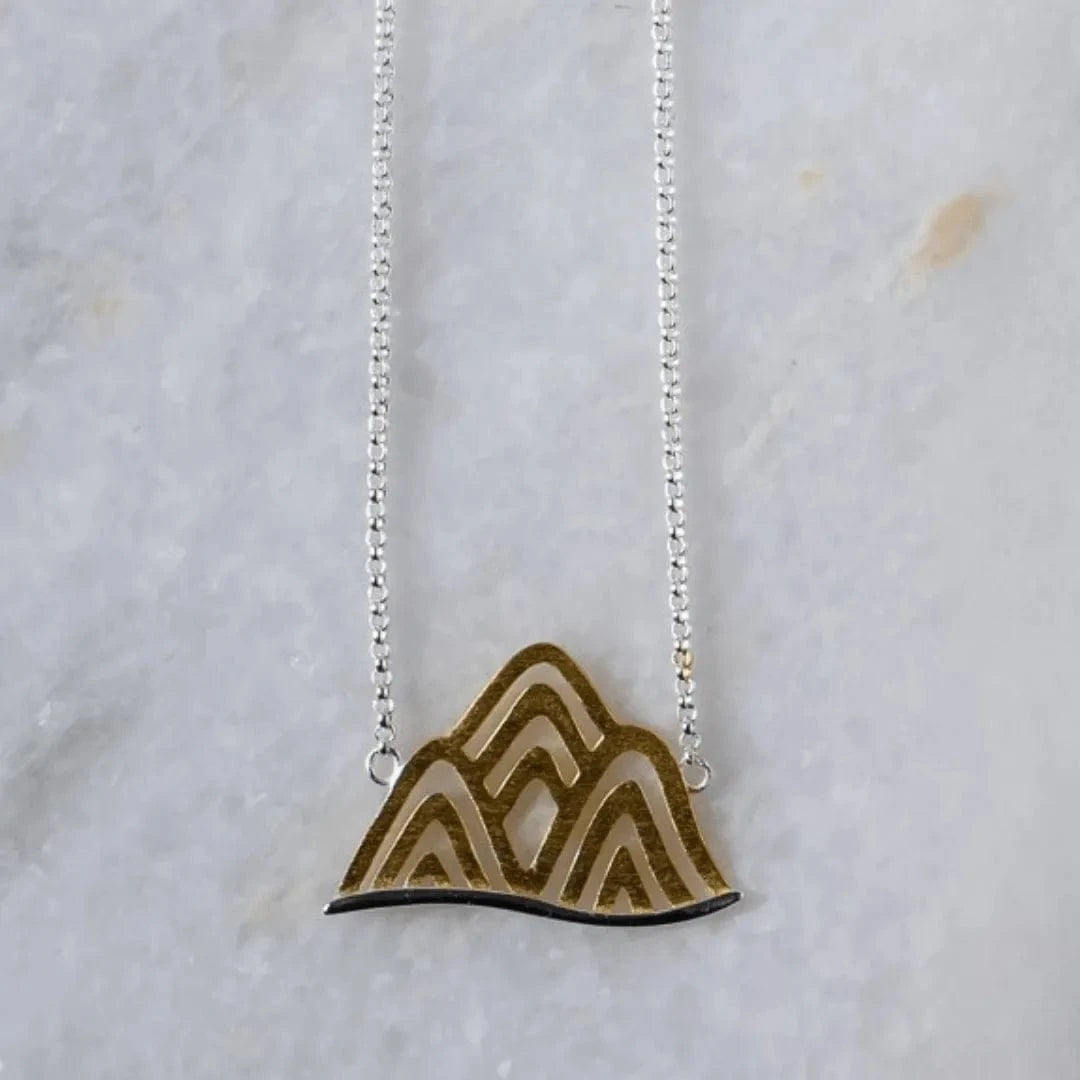 Necklace with a mountain-shaped pendant on a light gray background
