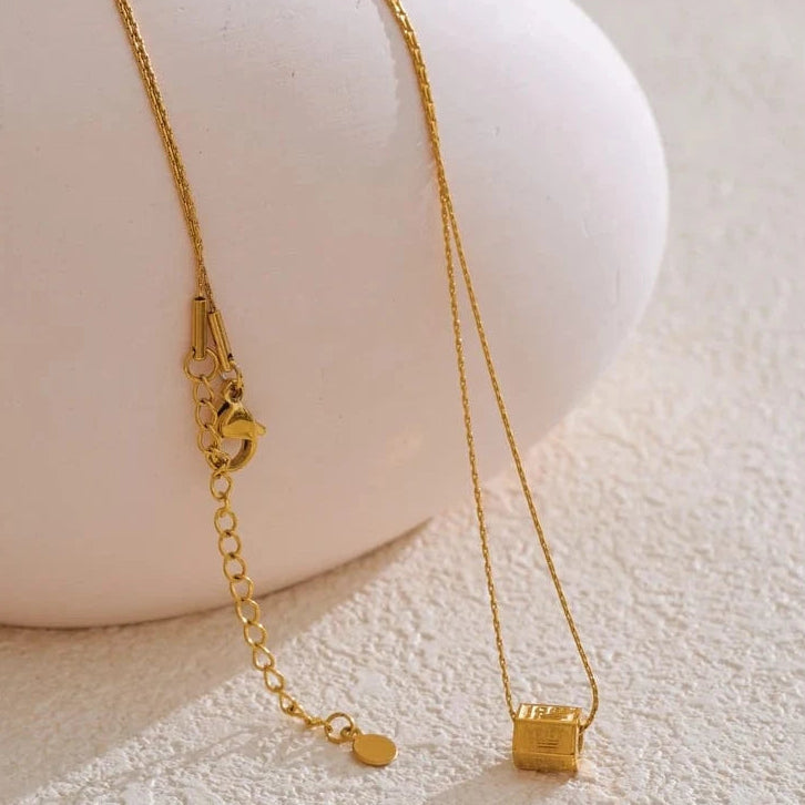 Gold necklace on a white mannequin bust with a neutral background