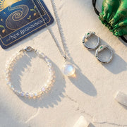 Jewelry set including a necklace, bracelet, and rings on a textured surface  