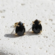 Pair of black teardrop earrings with gold posts on a white background