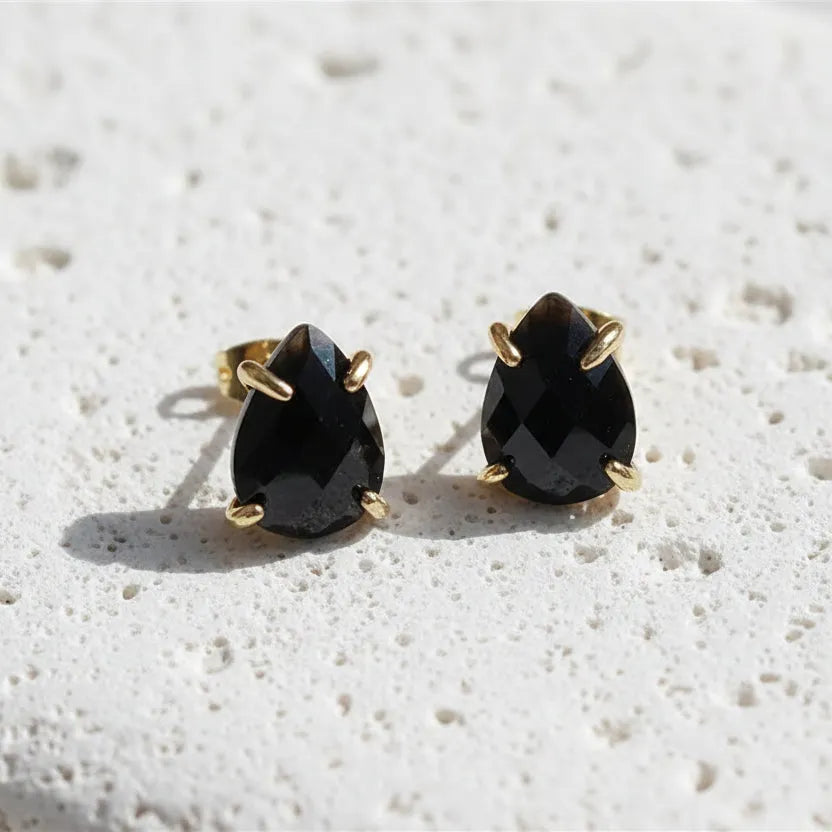Pair of black teardrop earrings with gold posts on a white background