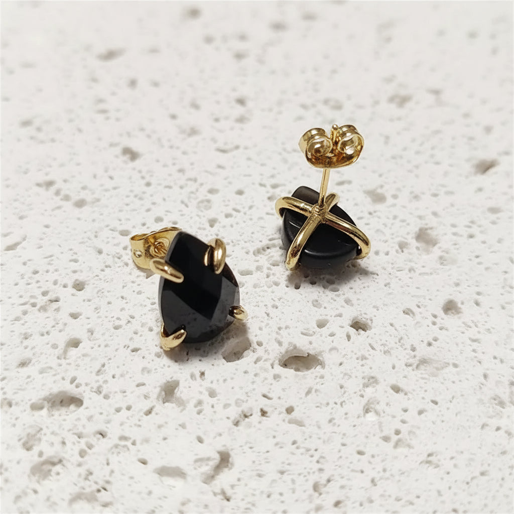 Gold earrings with black gemstones on a white background