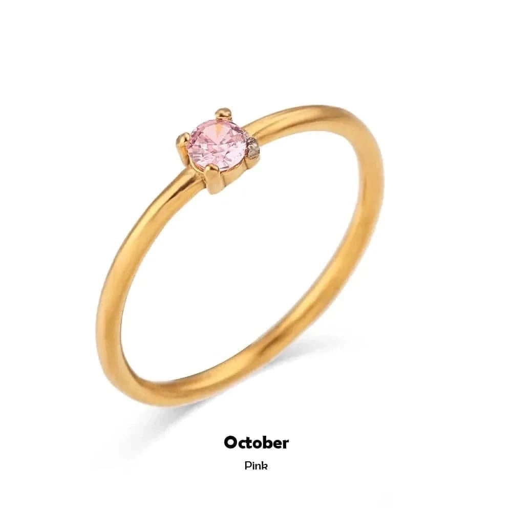 Gold ring with a pink gemstone on a white background, labeled 'October Pink'.