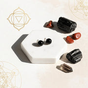 Black earrings on a white hexagonal stand with crystals on a light background