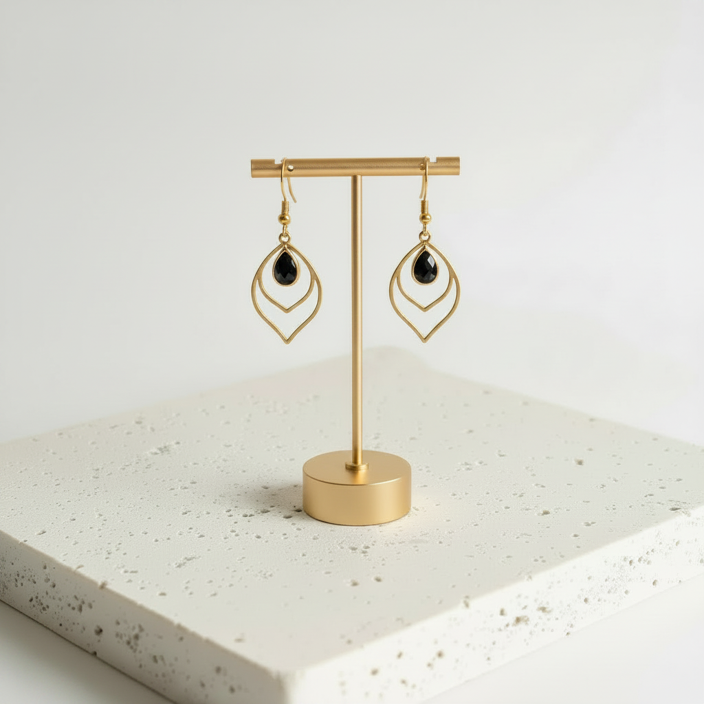 Black faceted glass teardrop earrings in gold, shown hanging