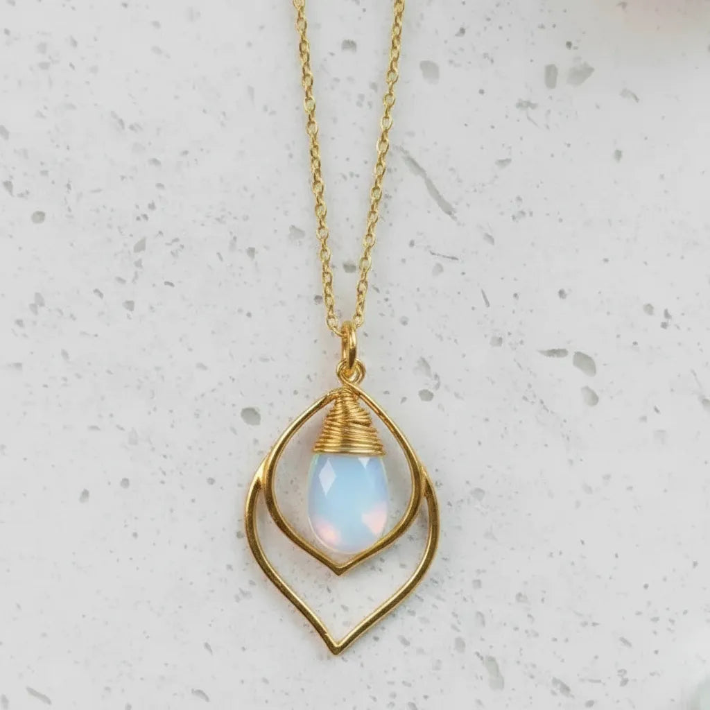 Necklace with a gold pendant featuring an opal stone on a light gray background