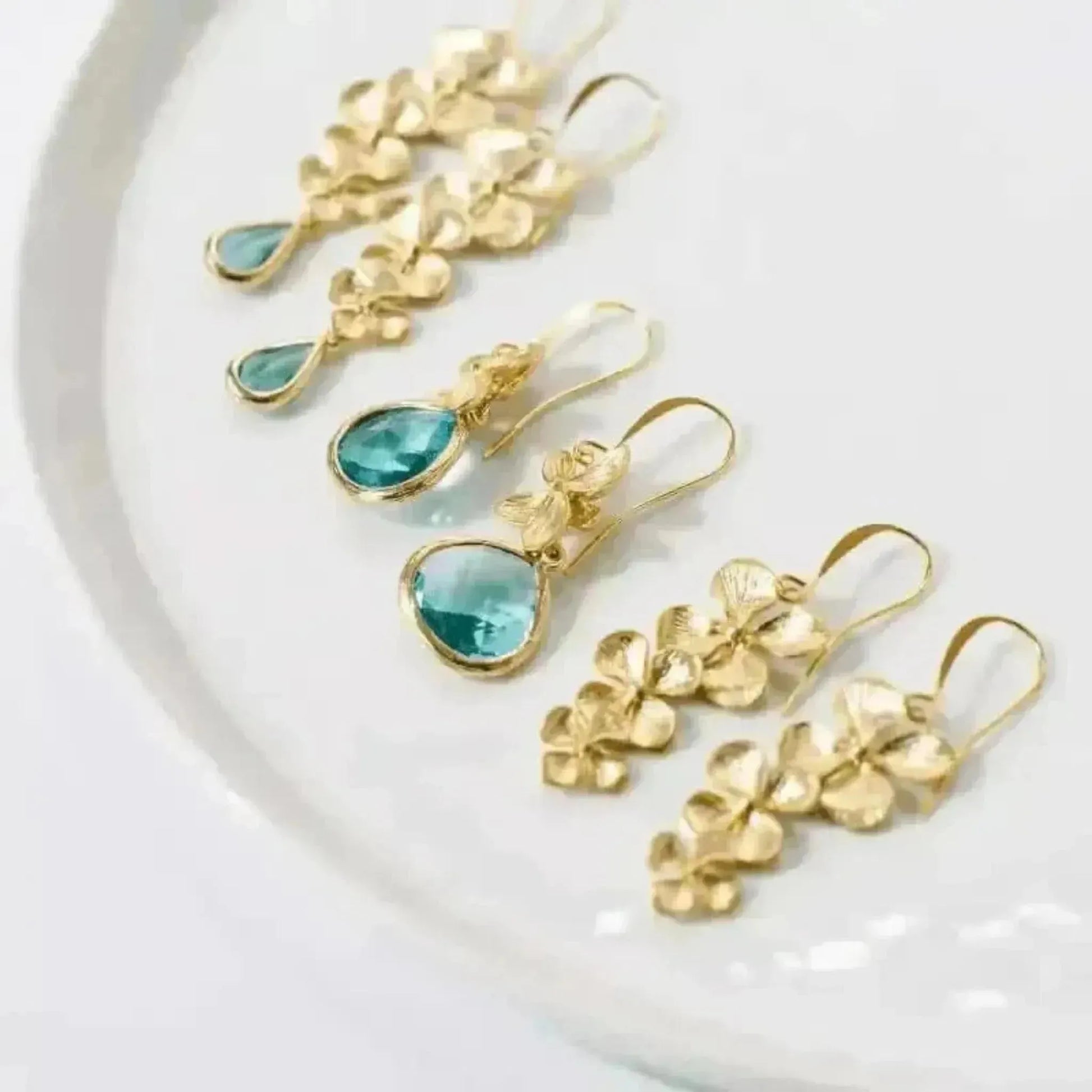 Gold earrings with blue gemstones on a white plate