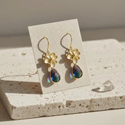 Gold floral earrings with colorful teardrop-shaped stones on a display card.