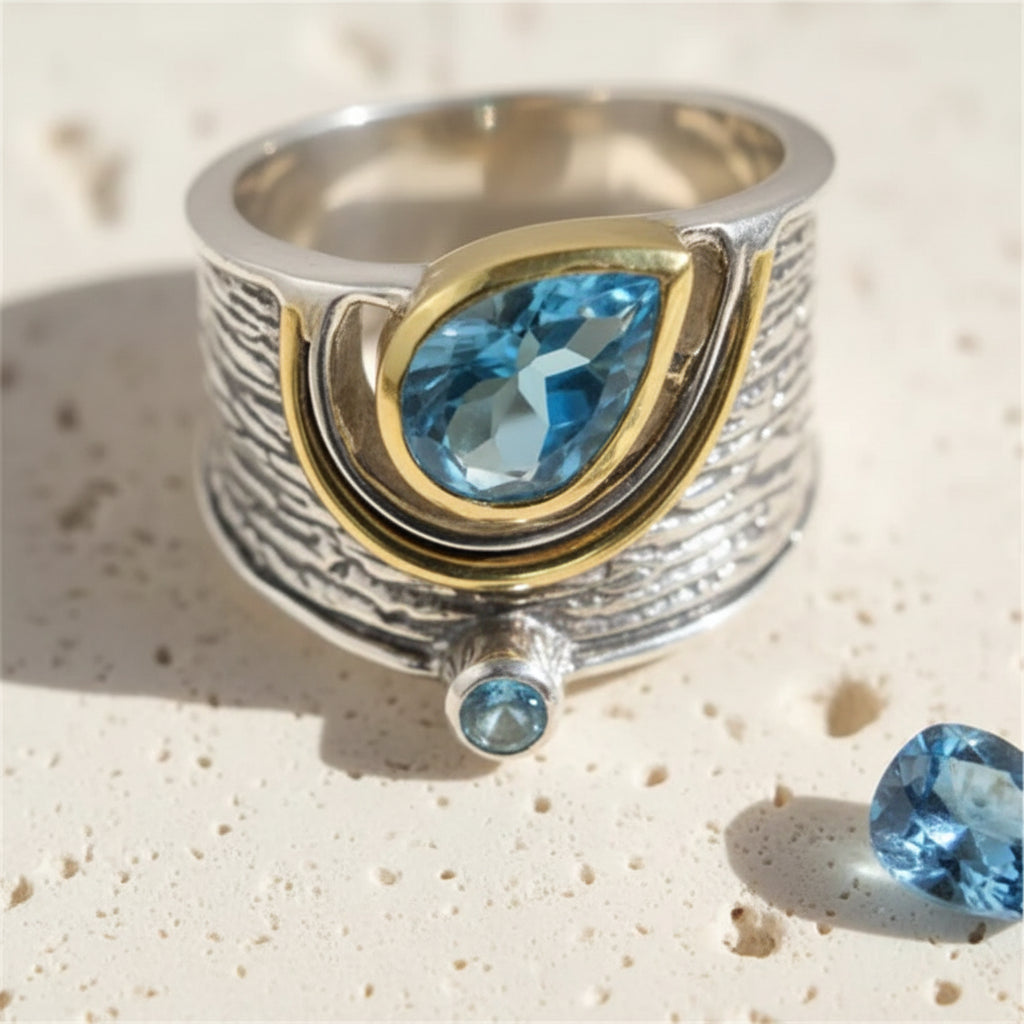 Blue pear-cut statement ring, 8 mm stone on a 15 mm two-tone textured band, sizes 6 to 10