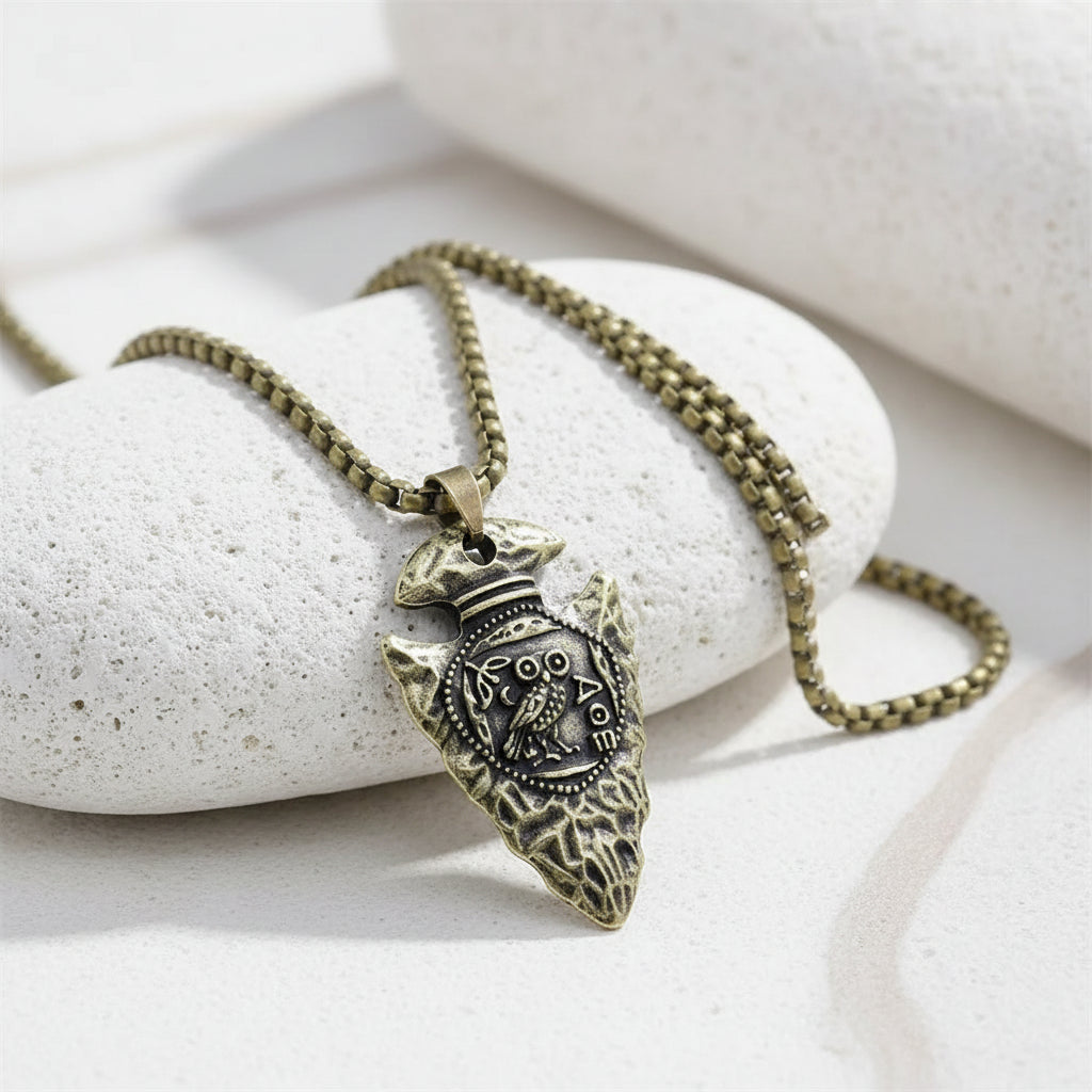 brass owl pendant on a chain against a white background