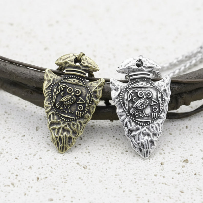 Two silver and gold owl pendants on white background