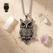 Silver owl pendant necklace on a stone surface with crystals