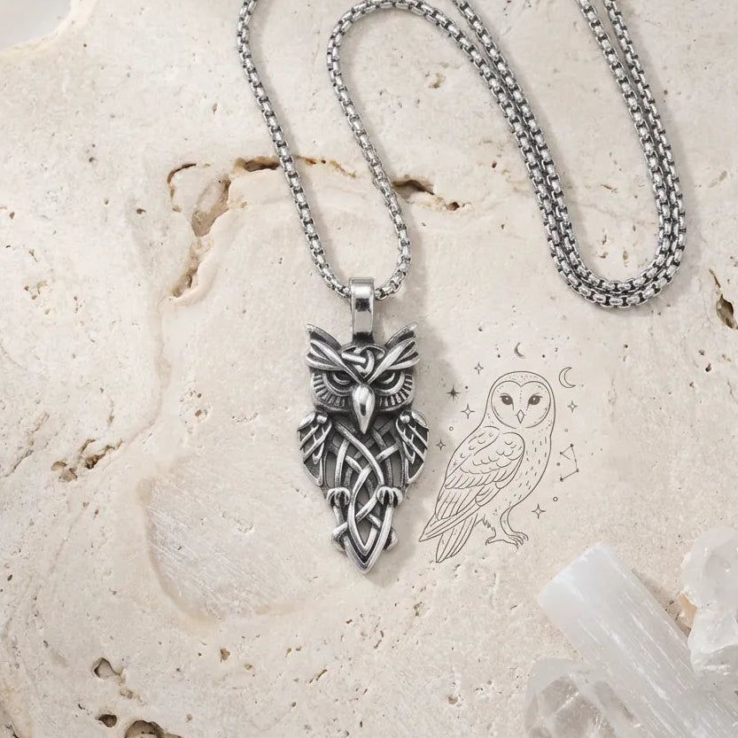 Silver owl pendant necklace on a stone surface with an illustration of an owl.