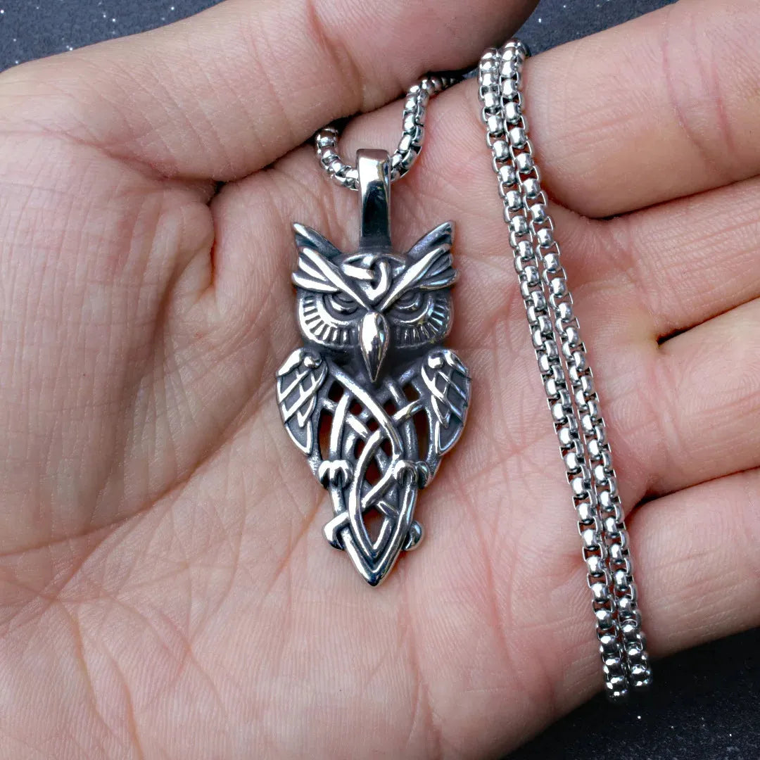 Silver owl pendant on a chain held in a hand