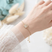 Gold bracelet with paw design on a wrist against a blurred background