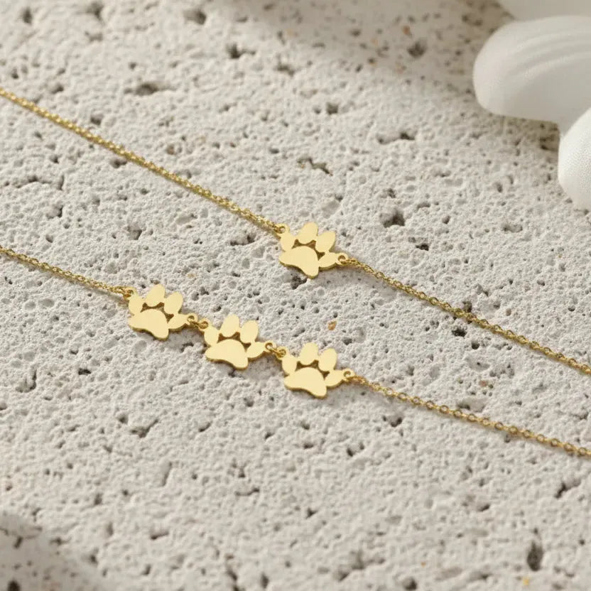 Gold pet name bracelets on a green surface