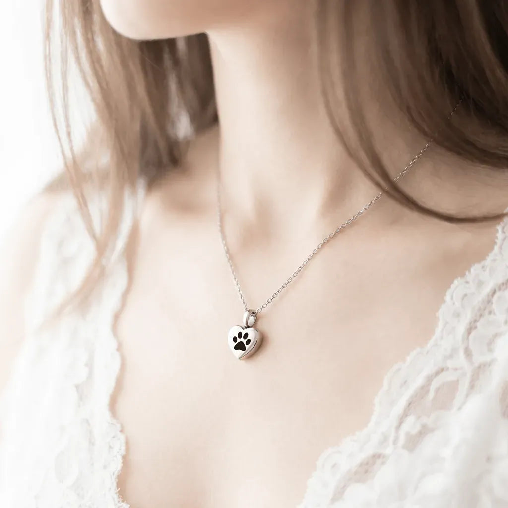 Necklace with a paw print pendant worn by a person in a white lace top.