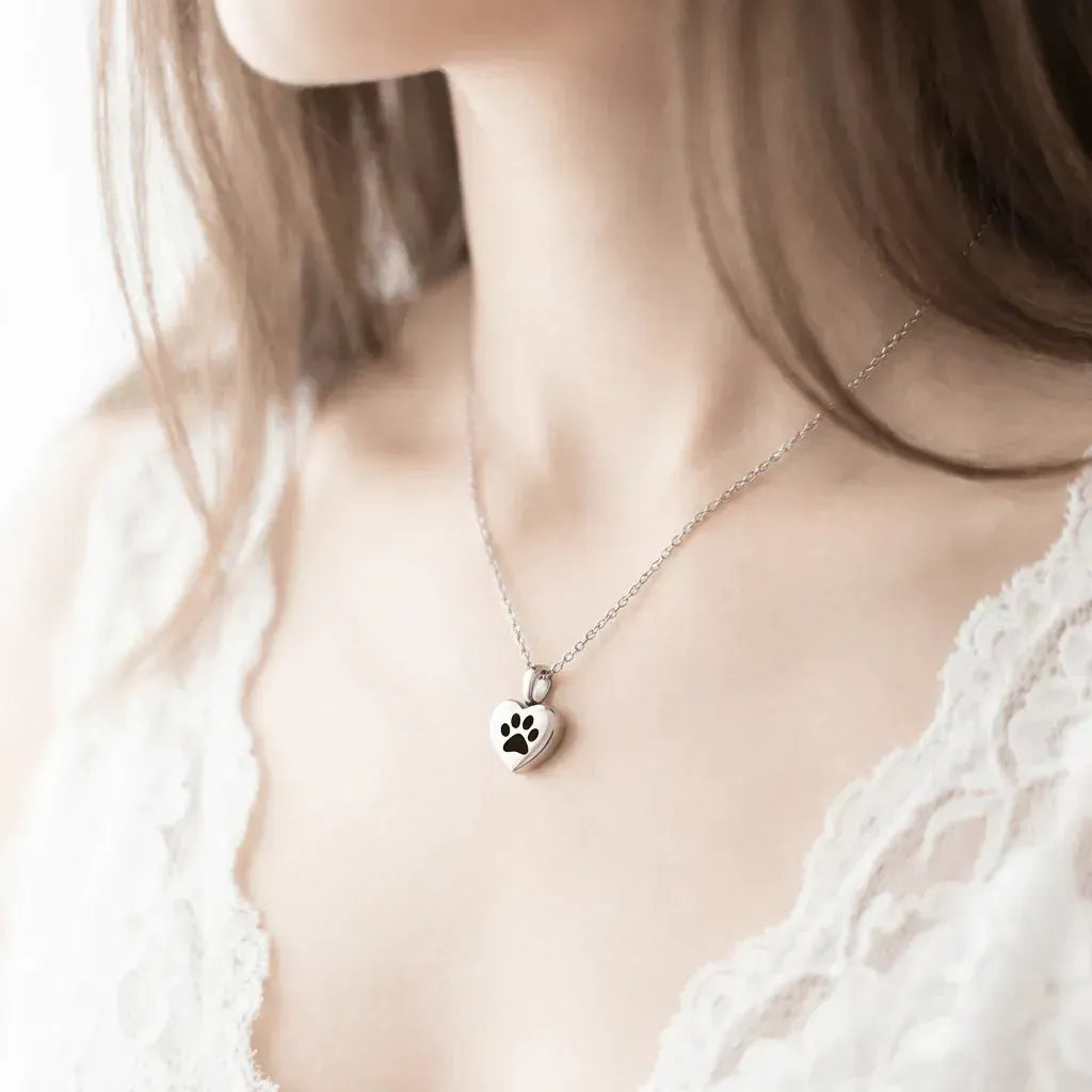 Necklace with a paw print pendant worn by a person in a white lace top.