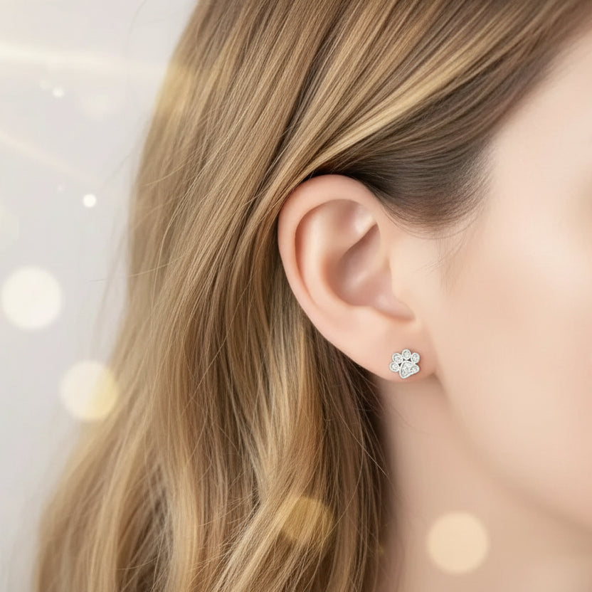 Close-up of an ear wearing a diamond earring with dark hair and light skin.