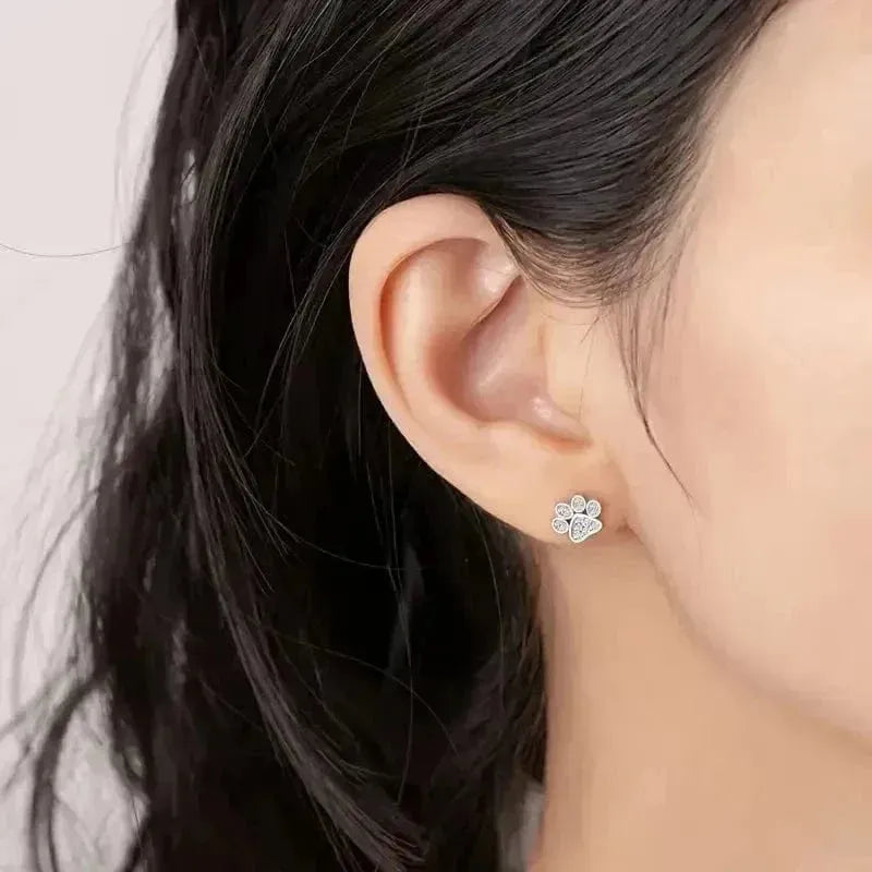Close-up of an ear wearing a diamond earring with dark hair and light skin.