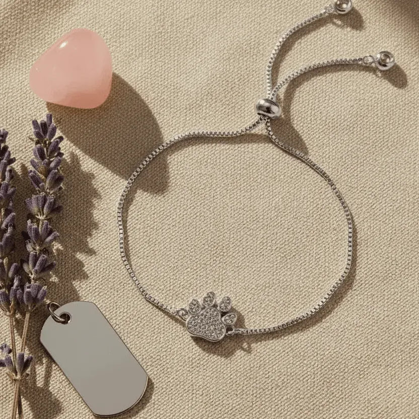 Silver bracelet with paw charm and pink heart on beige surface