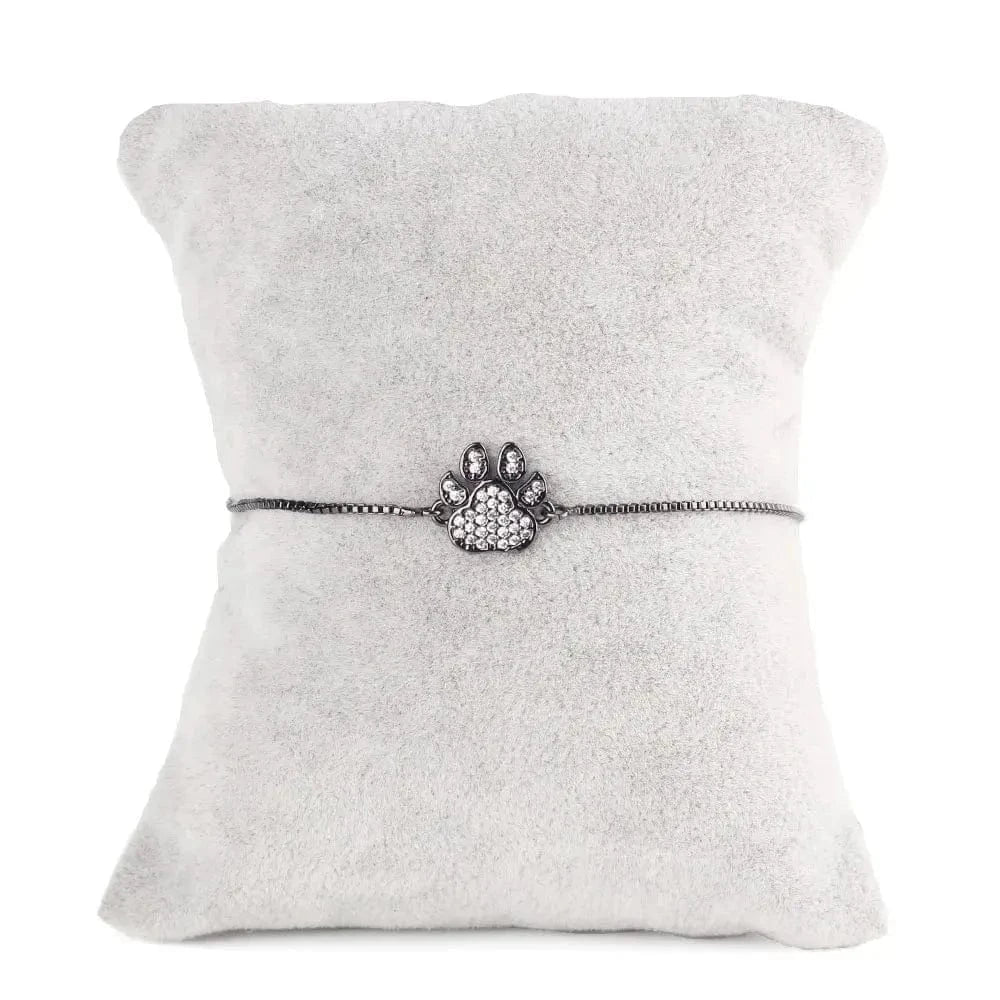 Silver bracelet with paw charm on a gray cushion