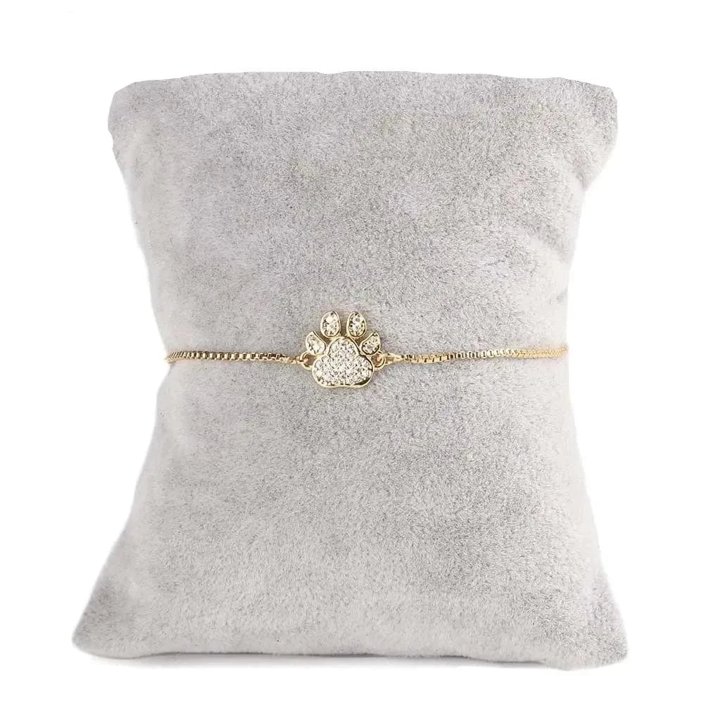 Gold bracelet with paw design on a gray 