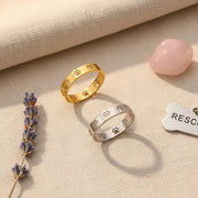 Gold and silver paw print rings on a beige background